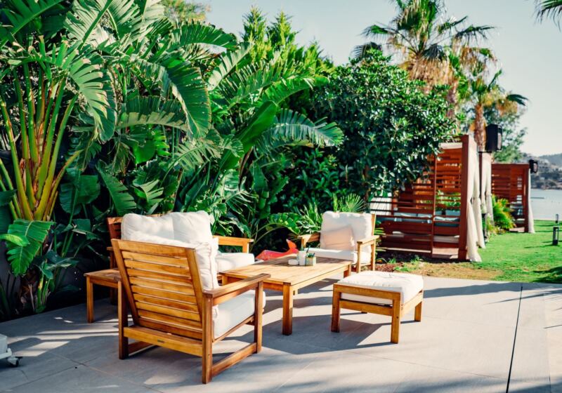 Patio furniture on a stone terrace surrounded by plants