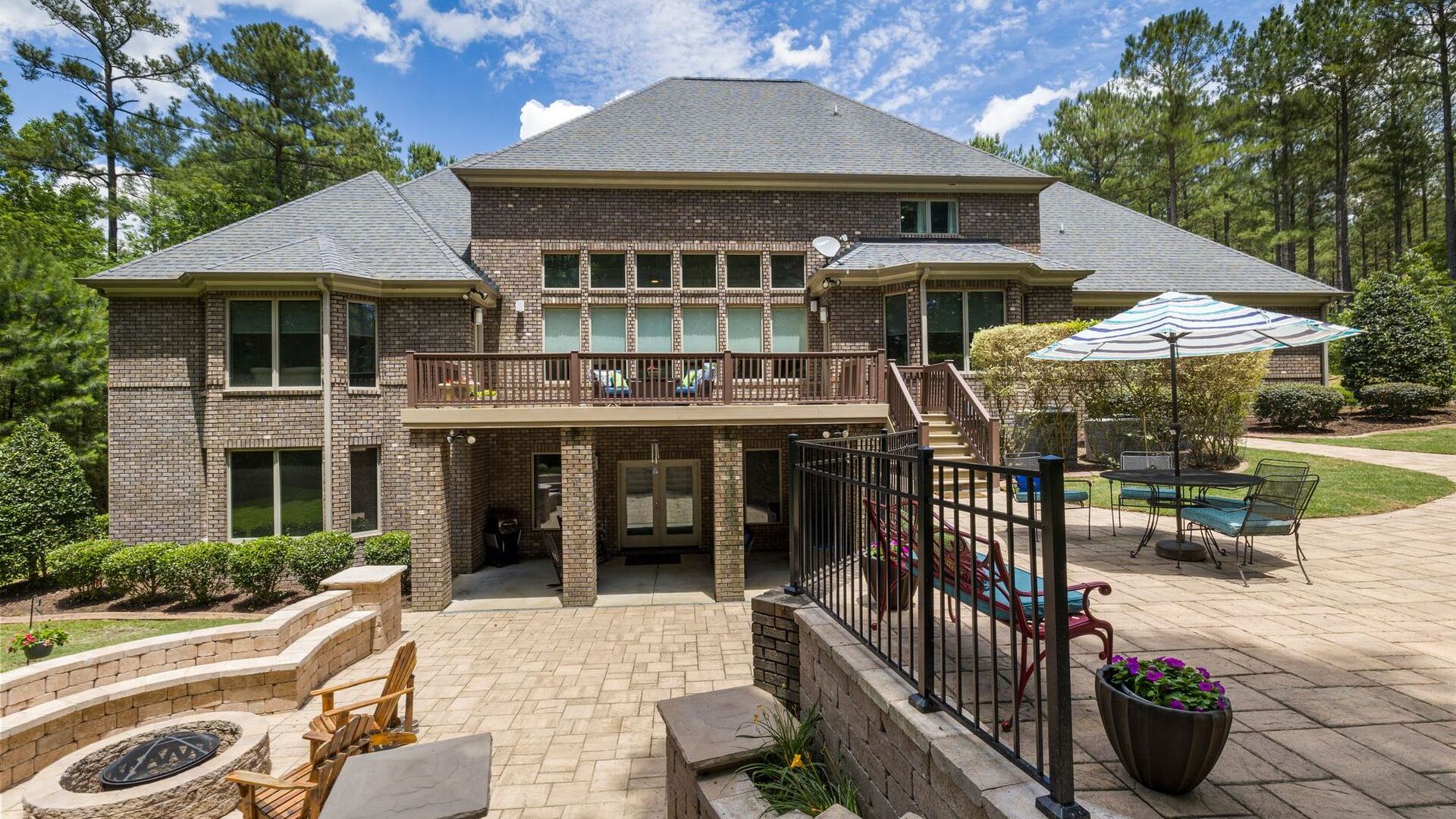 Stone patio with fire pit behind a two-storey home