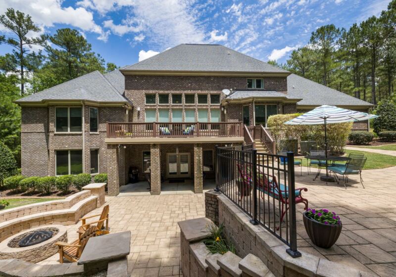 Stone patio with fire pit behind a two-storey home
