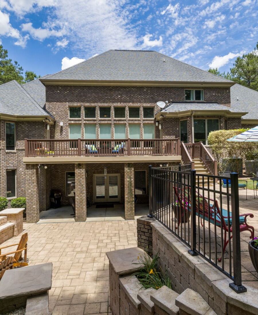 Stone patio with fire pit behind a two-storey home